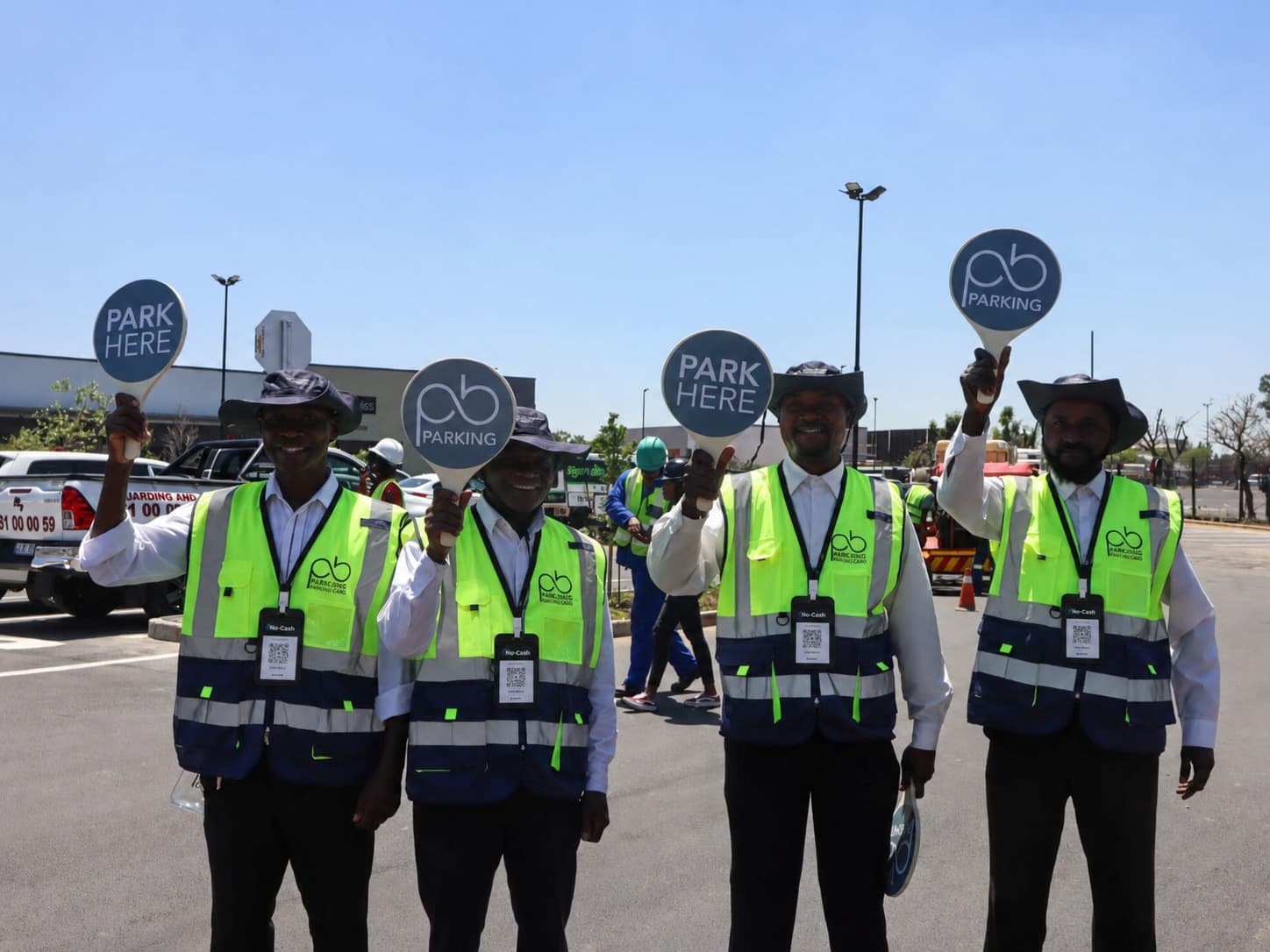Car guards wearing NoCash QR code lanyards at a South African shopping centre